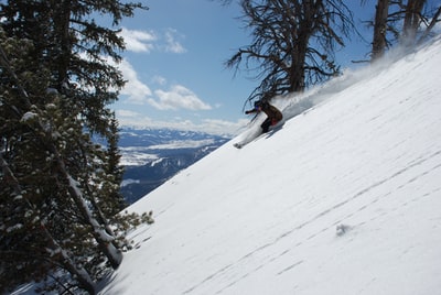 白天在积雪覆盖的下坡上滑行的人用滑雪板